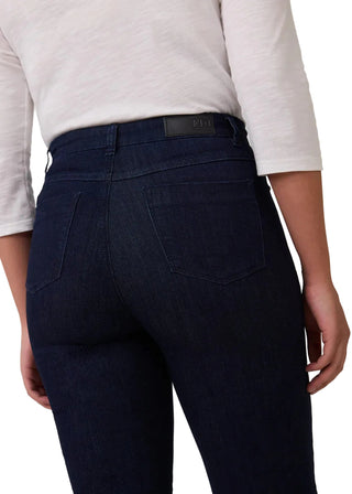 Person wearing dark blue jeans with a visible brand logo on a plain background