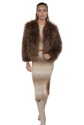 Woman wearing a brown fur coat, beige top, and skirt on a white background