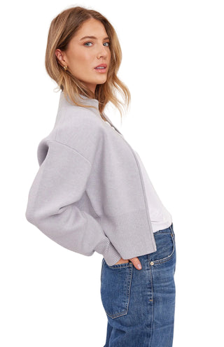 Woman wearing a light gray sweater and blue jeans on a white background