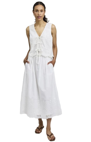 Woman wearing a white dress with lace details on a plain background