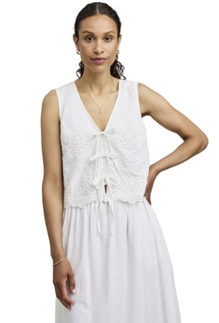 Woman wearing a white sleeveless dress against a plain background