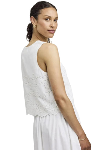 Woman wearing a white sleeveless top with cut-out details on a plain background