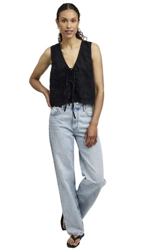 Woman wearing a black sleeveless top and light blue jeans on a white background