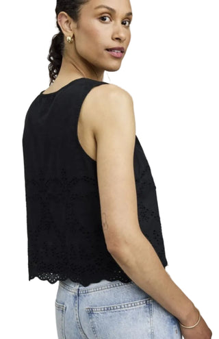 Woman wearing a black sleeveless top with lace details on a plain background