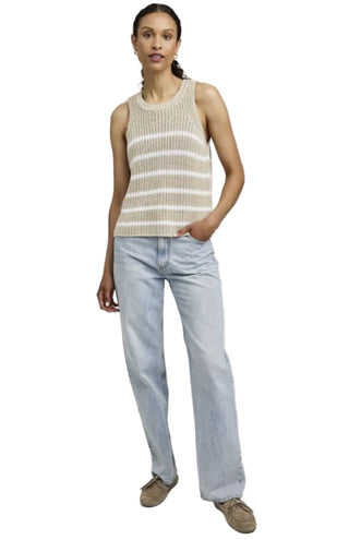 Woman wearing a striped sleeveless top and light blue jeans on a white background
