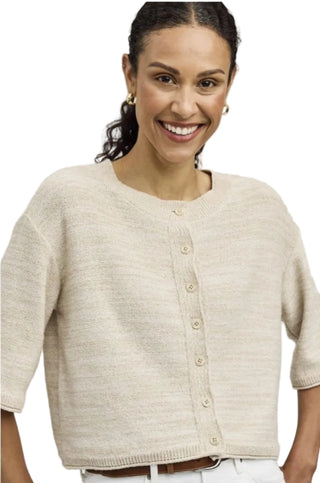 Woman wearing a beige cardigan against a plain background