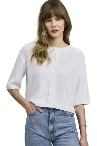 Woman wearing a white blouse and blue jeans against a plain background