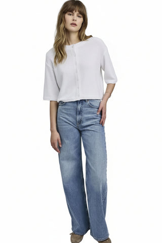 Woman wearing a white blouse and blue jeans on a plain background