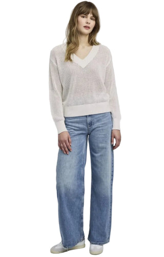 Woman wearing a light pink sweater and blue jeans on a white background