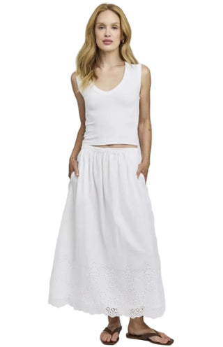 Woman wearing a white sleeveless top and skirt on a plain background