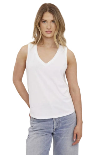 Woman wearing a white tank top and light blue jeans on a plain background