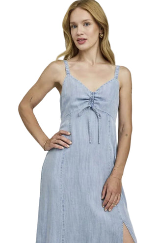 Woman wearing a light blue denim dress on a plain background