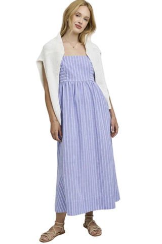 Woman wearing a blue striped dress with a white cardigan on a light gray background