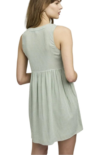 Woman wearing a green checkered dress against a plain background