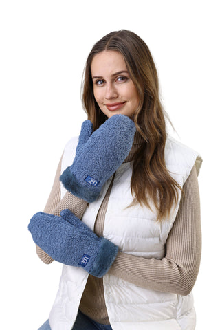 Woman wearing blue mittens and a white vest against a light background