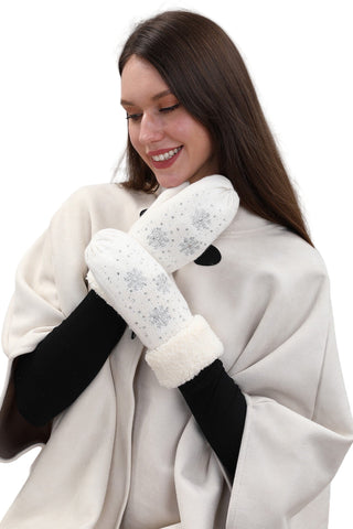 Woman wearing white mittens with black accents and a white coat against a light background