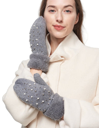 Woman wearing gray mittens with pearl embellishments on a white background