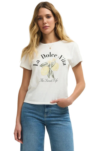 Woman wearing a white t-shirt with 'La Dolce Vita' and lemon graphic, standing against a plain background.