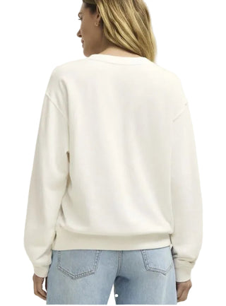 Person wearing a white sweatshirt and light blue jeans on a plain background