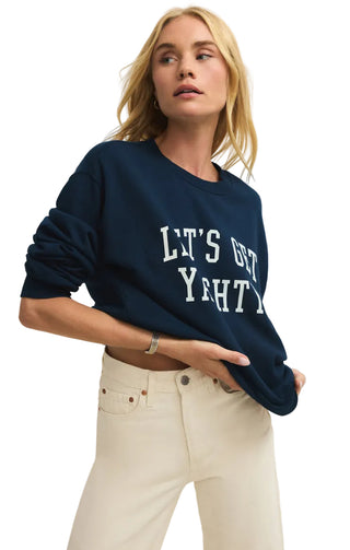 Woman wearing a navy blue sweatshirt with text, standing against a plain background