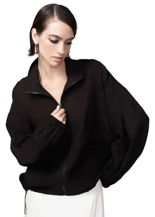 Woman wearing a black oversized sweater against a light gray background