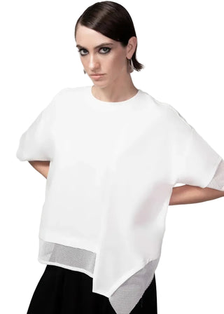 Woman wearing a white blouse with sheer sleeves against a gray background