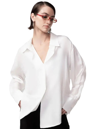 Person wearing a white blouse and red glasses on a plain background