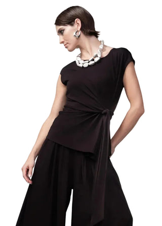 Woman wearing a black dress with a knot detail on a gray background