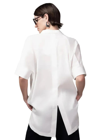 Person wearing a white oversized shirt against a gray background