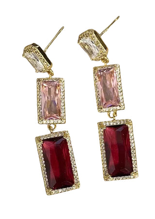 Pair of earrings with pink and red gemstones on a textured surface