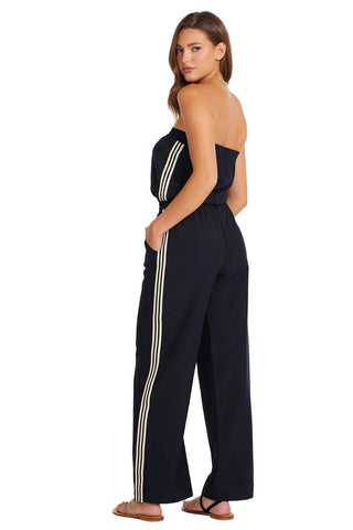 Woman wearing a navy jumpsuit with white stripes on a white background