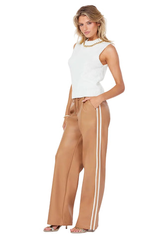 Woman wearing a white sleeveless top and tan pants with white stripes on a white background
