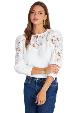 Woman wearing a white lace top and blue jeans on a white background