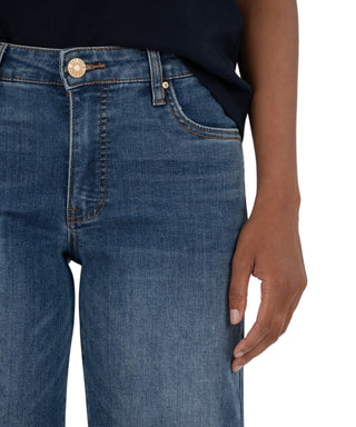 Close-up of blue jeans with a brand logo on a neutral background