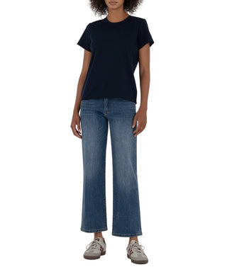 Person wearing a black t-shirt and blue jeans on a beige background