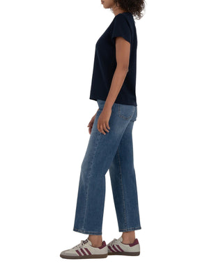 Person wearing a navy t-shirt and blue jeans on a beige background