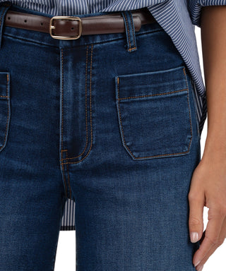 Close-up of blue jeans with a belt and striped shirt.