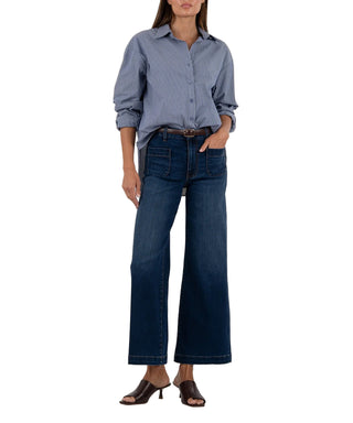 Person wearing a blue button-up shirt and dark blue jeans on a white background