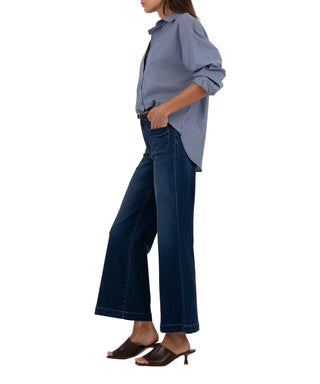 Person wearing a blue shirt and dark jeans on a white background