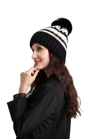 Woman wearing a black and white striped beanie with a pom-pom on a light gray background