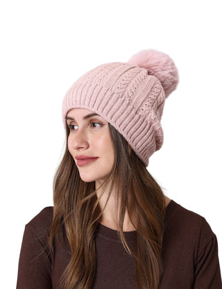 Woman wearing a pink knitted beanie against a plain background