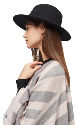 Woman wearing a black hat and striped shawl on a light gray background