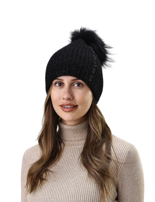 Woman wearing a black knit beanie with a pom-pom against a white background