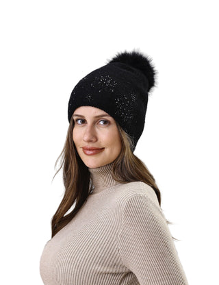 Woman wearing a black beanie with a pom-pom against a white background