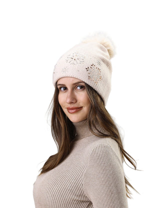 Woman wearing a beige knit beanie with a pom-pom against a light gray background
