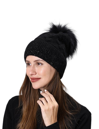Woman wearing a black knit beanie with a pom-pom on a light gray background
