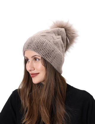 Woman wearing a beige knitted beanie with a pom-pom on a white background