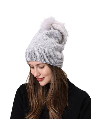Woman wearing a gray knit beanie with a pom-pom on a light gray background