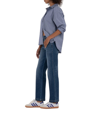 Person wearing a blue shirt and jeans with white sneakers on a beige background