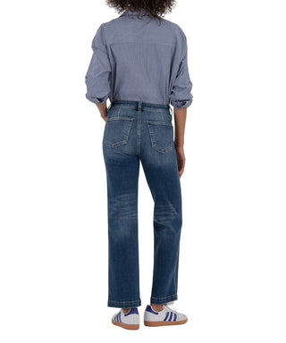 Person wearing a blue denim shirt and jeans on a beige background